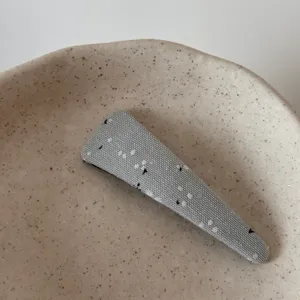 Detail view of a chic grey fabric geometric snap hair clip, stylish and versatile hair accessory.