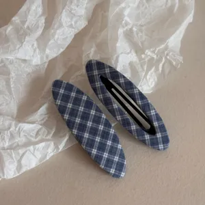 Detailed close-up of a cute blue and white plaid hair clip, perfect for side hair styling.