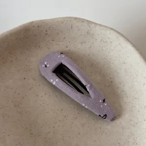 Charming purple fabric snap hair clip with delicate small print, close-up view detail.