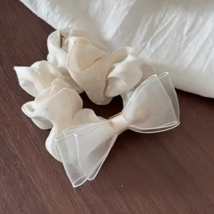 Detailed view of a creamy white organza bow hair scrunchie with cute polka dots design.