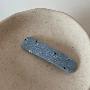Blue fabric hair clip detail shot, cute floral pattern side clip for daily hairstyles and cute looks.