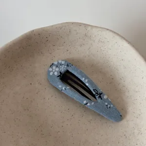 Close-up of blue floral fabric BB hair clip detail placed in minimalist ceramic dish.