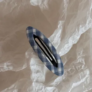 Detailed close-up of a blue and white checkered fabric snap hair clip, stylish accessory.