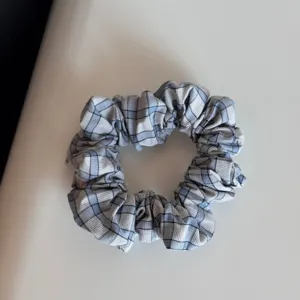 Blue and white plaid fabric hair scrunchie, classic checkered hair tie detail for daily styling.