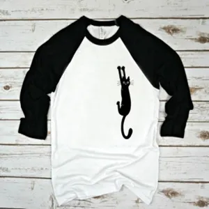 Black and white raglan sleeve T-shirt with cute hanging cat graphic detail view.