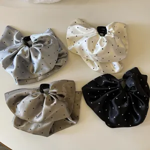 Gros plan détaillé d'élégantes pinces à cheveux en satin à pois montrant la texture fine.