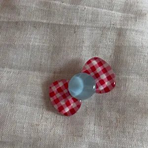 Χαριτωμένο παιδικό τσιμπιδάκι μαλλιών με κόκκινο λευκό καρό φιόγκο και μπλε κέντρο.