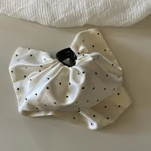 Gros plan detaille montrant la texture satinee elegante et la pince a cheveux a pois.