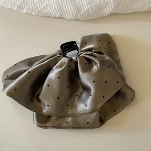 Vue rapprochée détaillée de la pince à cheveux en satin à pois avec nœud en tissu.
