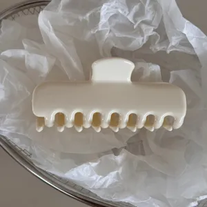 Detailed shot of a minimalist milky white hair claw clip placed on white tissue paper.
