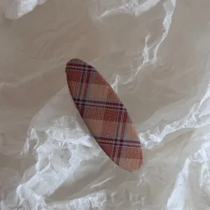 Vista detallada de una pinza de pelo de tela a cuadros, accesorio retro elegante para peinados.