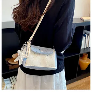 Detail view of a fresh blue and white star pattern crossbody bag with a cute star pendant.