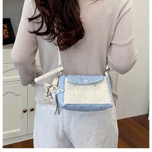 Detail shot of a stylish light blue and white star pattern crossbody bag worn by a model.