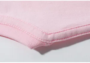 Primer plano detalle camiseta infantil rosa, costuras finas y tejido de algodón.