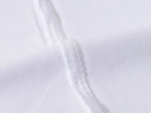 Primo piano del tessuto bianco della maglietta che mostra dettagli di cucitura puliti.