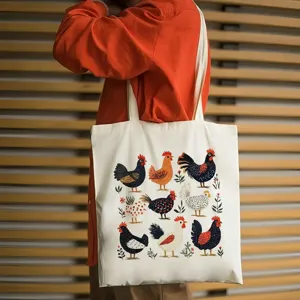 Détail du sac cabas en toile avec imprimé coq vintage, porté devant un fond en bois.