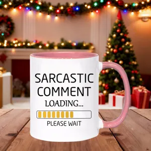 Detailed view of white ceramic coffee mug with funny text and pink handle on wood desk.
