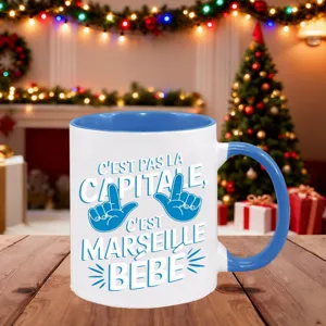 Vista detallada de la taza de cerámica azul y blanca con texto en francés y ambiente navideño.