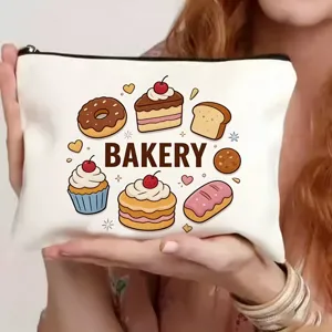 Detailopname van wit canvas cosmetisch tasje met schattige cartoon bakkerij print en ritssluiting.