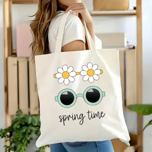Gros plan d'un sac cabas en toile blanche avec un joli imprimé marguerite et lunettes.