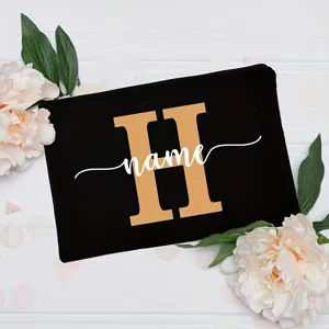 Custom black canvas makeup bag with gold letter monogram and stylish white cursive name text.