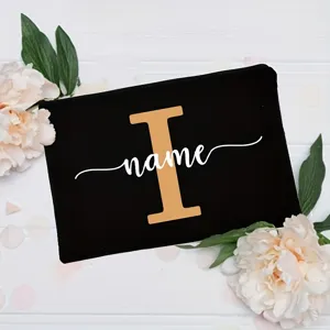 Customized floral alphabet black canvas cosmetic pouch with delicate peony and leaf background decor.