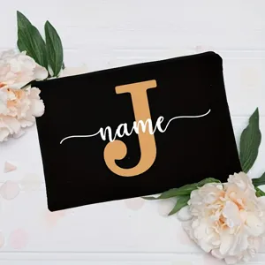 Detail view of the custom black canvas cosmetic bag featuring a bold gold letter and script name.