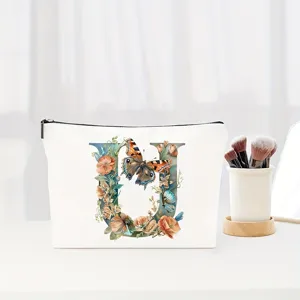 Close-up detail of the canvas makeup pouch featuring an elegant floral letter U and butterfly print.