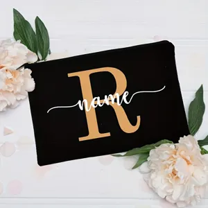 Detail shot of custom black canvas makeup pouch with gold letter R and white name print.