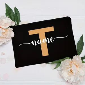 Detailed close-up of a personalized black canvas cosmetic pouch featuring a custom letter and text design.