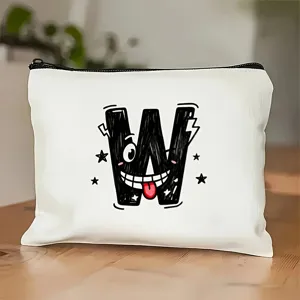 Detailopname van witte cosmetische tas met speelse zwarte W-letterprint op houten tafel.