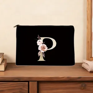 Close-up detail of the black cosmetic pouch featuring a custom gold letter P and floral print.