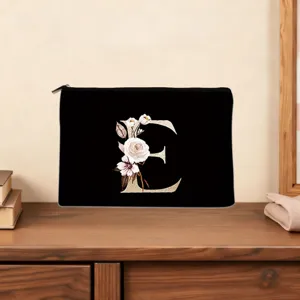 Black canvas cosmetic bag featuring a floral letter E design, elegant zipper clutch pouch.