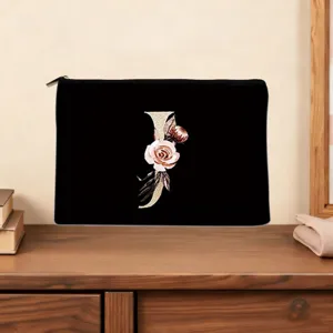 Floral letter J cosmetic pouch detail, showing elegant gold monogram and black canvas fabric close-up.