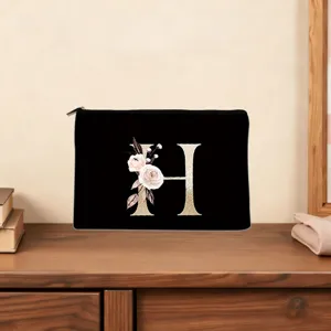 Black cosmetic bag with elegant gold letter H and floral design, perfect for daily use.