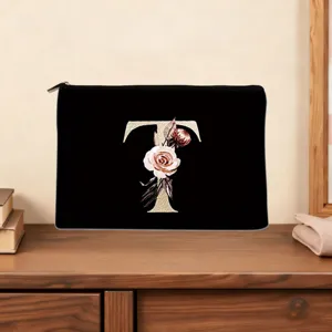 Detailed view of black cosmetic pouch featuring golden letter T and floral design.