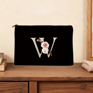 Detail shot of the elegant black custom letter W makeup bag with floral accents on wood desk.