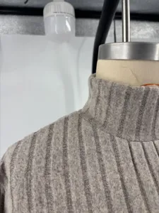 Close-up detail of grey ribbed turtleneck knit dress collar and shoulder texture.