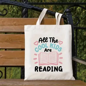 Canvas tote bag detail showing creative reading typography print and sturdy straps on bench.