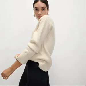Detailed view of the cozy V-neck ribbed knit sweater in off-white, soft winter texture.