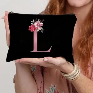 Close-up detail of black canvas cosmetic pouch with sparkling pink letter L and floral print.