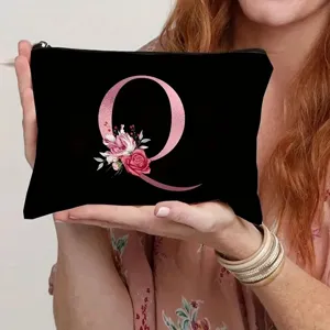 Detail view of a black canvas makeup bag featuring a stylish pink floral letter Q print.