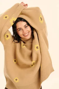 Detail view of a cozy camel knit sweater featuring yellow floral jacquard and high neckline.