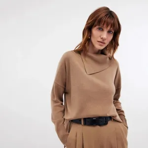 Detail view of the elegant camel turtleneck sweater featuring an asymmetric collar and soft fabric.