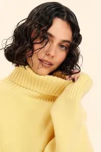 Close-up detail of women's yellow turtleneck knitted sweater, soft fabric and cozy winter style.