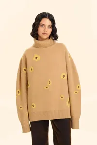 Close up detail of the camel turtleneck sweater showing soft knit texture and floral pattern.