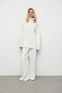 Vue détaillée d'un pull-over col roulé ample pour femme en blanc uni, texture douce.