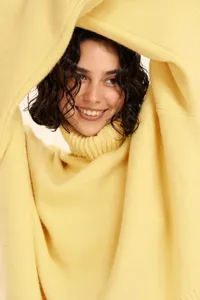 Closeup view of women's yellow turtleneck sweater, soft knit fabric texture and cozy collar.