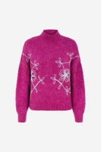 Detail view of a fuchsia mock neck knit sweater featuring intricate white floral embroidery.