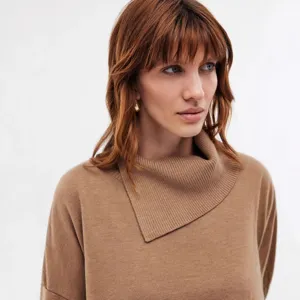 Close-up detail of the camel turtleneck knit sweater showcasing soft textured fabric.
